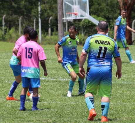 adultos jugando futbol en cancha de grama natural