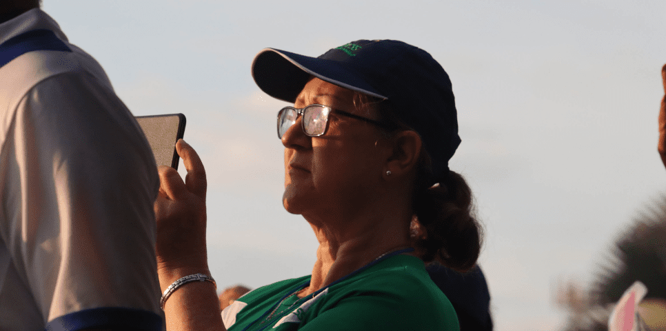 Mujer mayor con gafas grabando con un celular el cielo