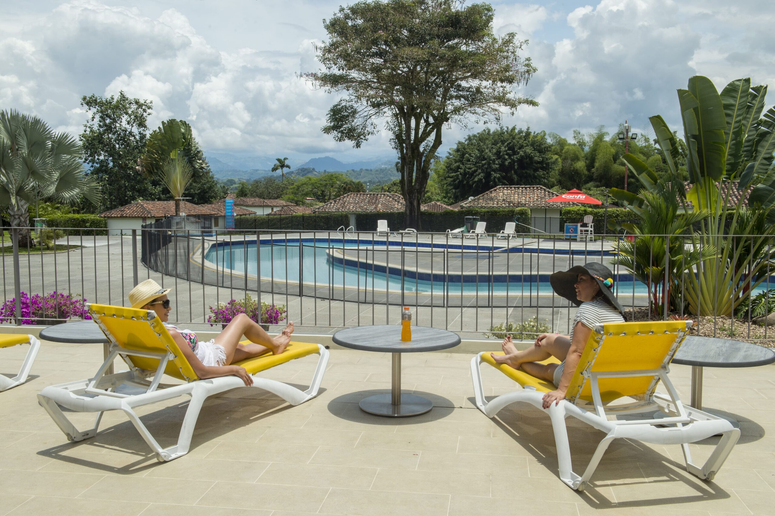 Dos mujeres toman en sol frente a la piscina