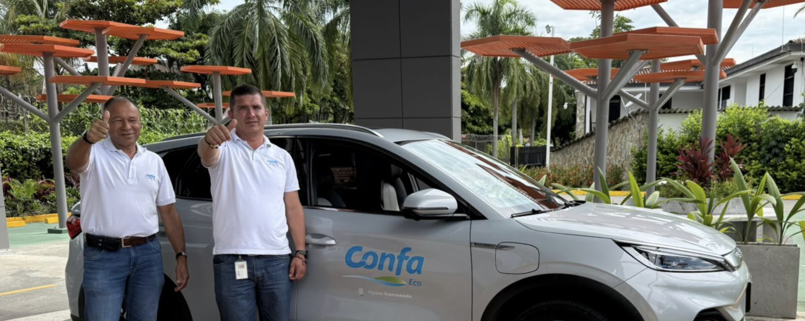 Colaboradores de Confa posan felices junto a uno de los carros eléctricos esto es sostenibilidad Confa.