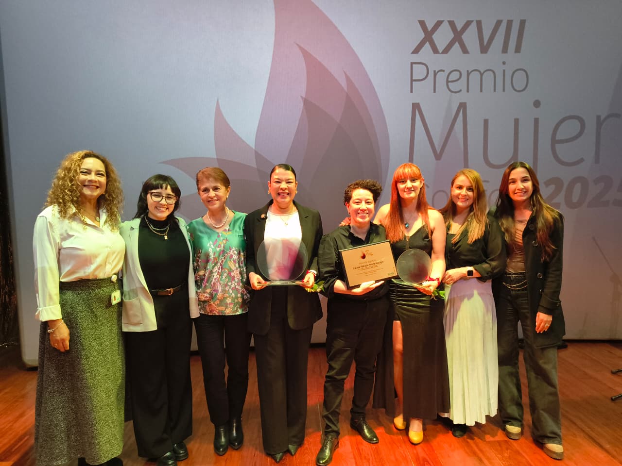 Mujeres sonrien posan con premio