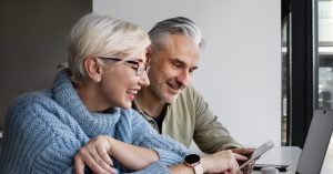 Dos personas, hombre y mujer, adultas, sonrién mientras solicitan su crédito en Confa