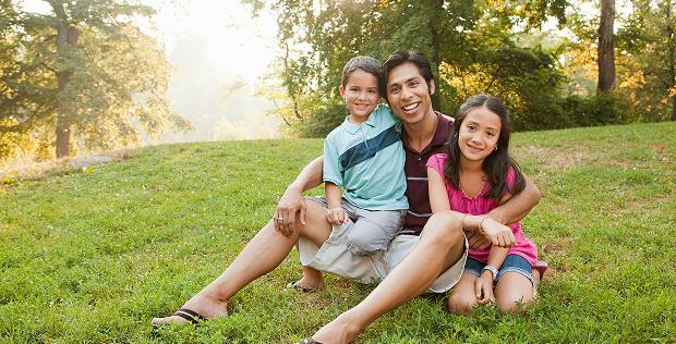 Familia sentada en un parque verde con arboles de fondo